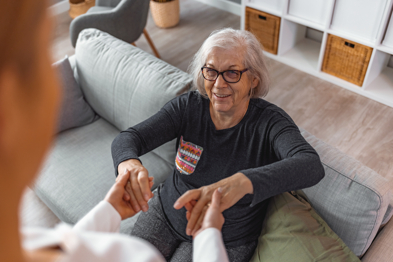 Caregiver smiling and talking to aged woman while taking care of her at home - stock photo
Photo of female professional caregiver taking care of elderly woman at home