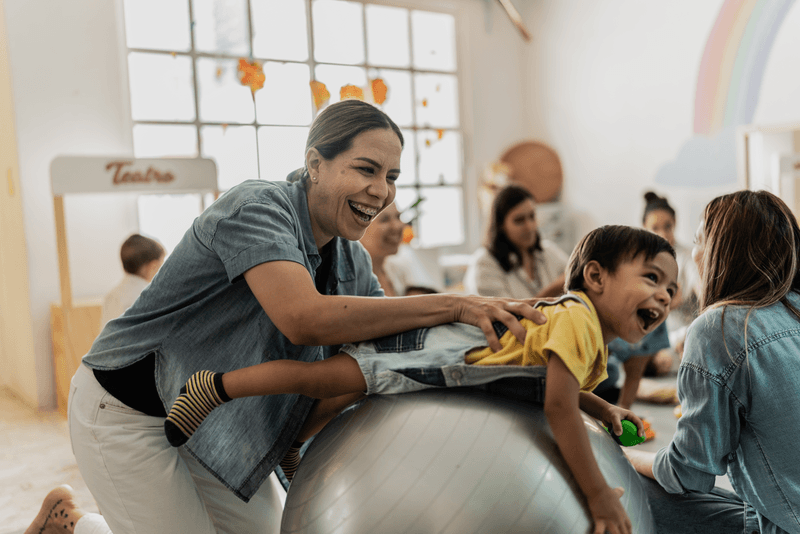 woman playing with child on ball