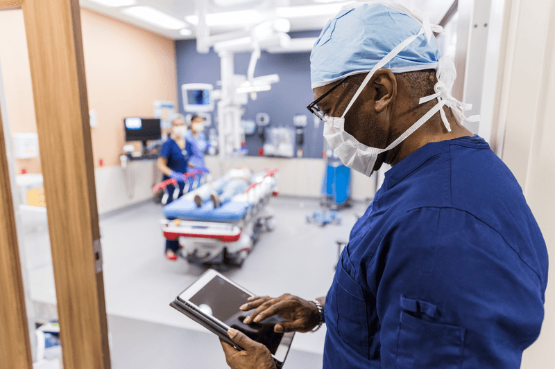 Before entering examination room, doctor reviews patient test results - stock photo
Before entering the emergency examination room, the mature adult doctor reviews the patient's test results on his digital tablet.