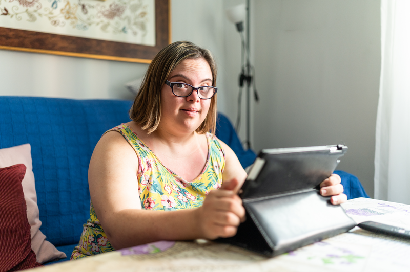 Smiling girl with down's syndrome using tablet at home - stock photo
Portrait of a cheerful girl with special needs using a digital tablet sitting on the sofa at home