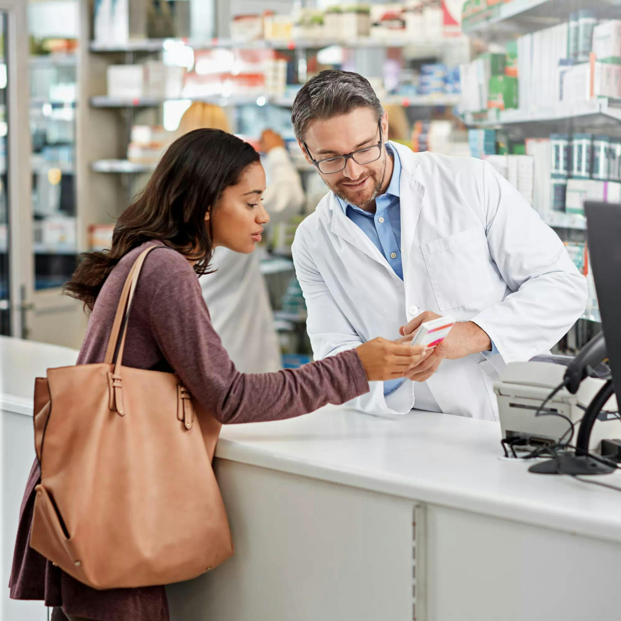 Shot of a male pharmacist assisting a customer at the prescription counter. All products have been altered to be void of copyright infringements